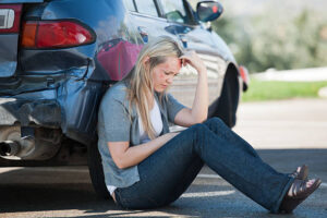 car accident victim sitting by car